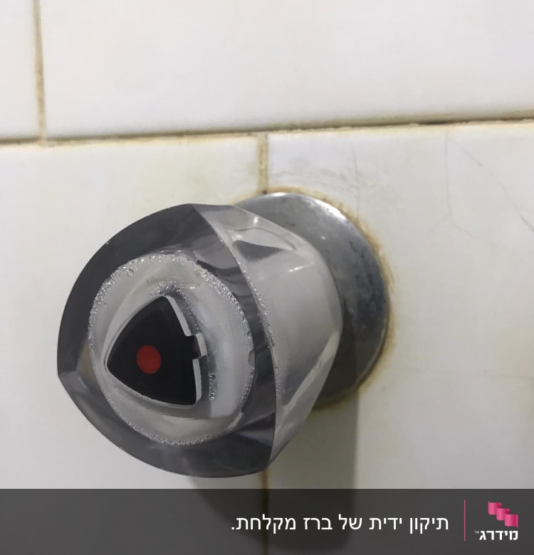 ידית ברז מים עם סימון אדום על קיר קרמיקה